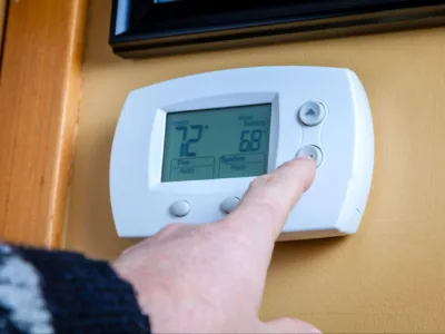 Person adjusting the thermostat in their home