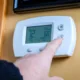 Person adjusting the thermostat in their home